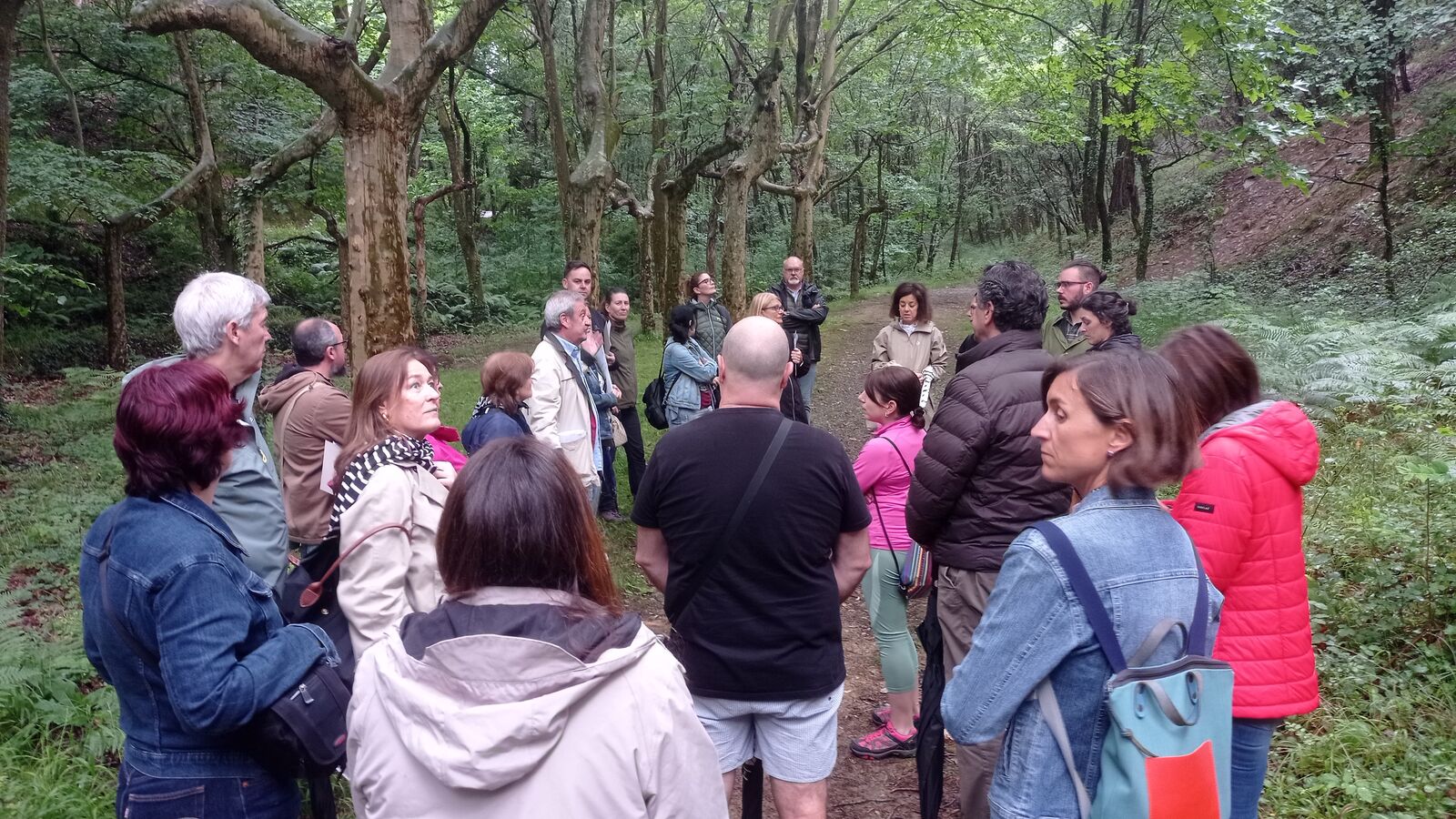 Grupo de asistentes atendiendo a las explicaciones en el arbolado de la finca